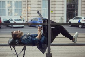 Legyen hasznos az utazással töltött idő! 1 young caucasian man bus stop lies bench with laptop his lap